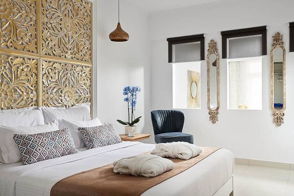 Schlafzimmer im Mythos Palace Resort & Spa mit einem großen Bett, goldenen Wandverzierungen und einem blauen Stuhl.