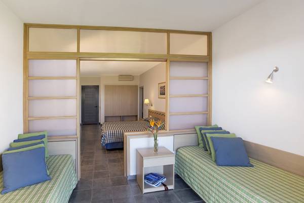 Schlafzimmer im Atlantica Mikri Poli Hotel auf Rhodos mit zwei Betten, Nachttischen und einem Schlafzimmer im Hintergrund.