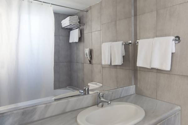 Badezimmer im Atlantica Mikri Poli Rhodes Hotel mit Spiegel, Waschbecken und Handtüchern.