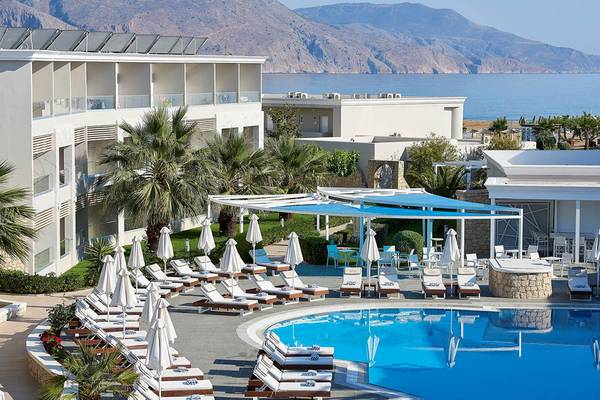 Außenbereich des Mythos Palace Resort & Spa mit Pool und Liegen vor der Kulisse von Bergen und Meer.