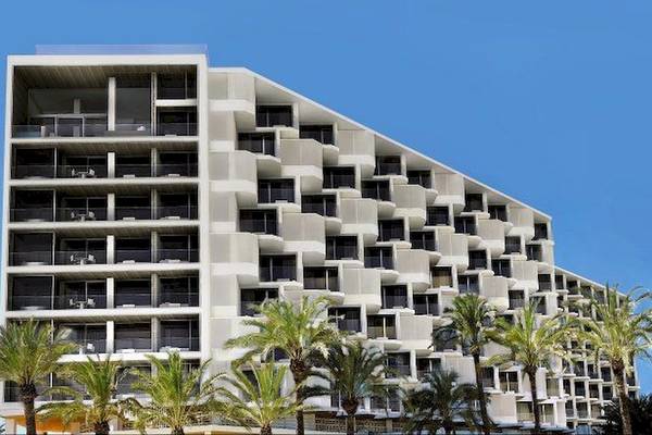 Außenansicht des Hard Rock Hotel Ibiza mit vielen Balkonen und Palmen davor.