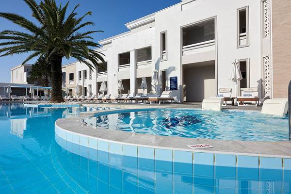 Außenpoolbereich des Mythos Palace Resort & Spa mit weißen Gebäuden und Sonnenliegen.