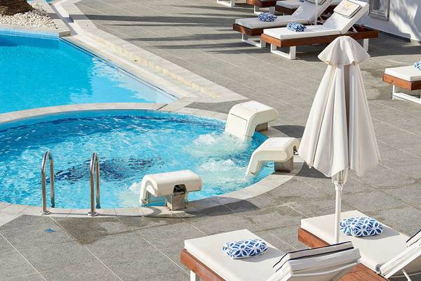 Außenpoolbereich des Mythos Palace Resort & Spa mit Liegen und Sonnenschirmen.