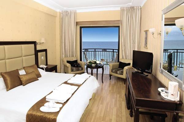 Zimmer im Constantinos the Great Beach Hotel mit Meerblick, Bett, Fernseher und Balkon.