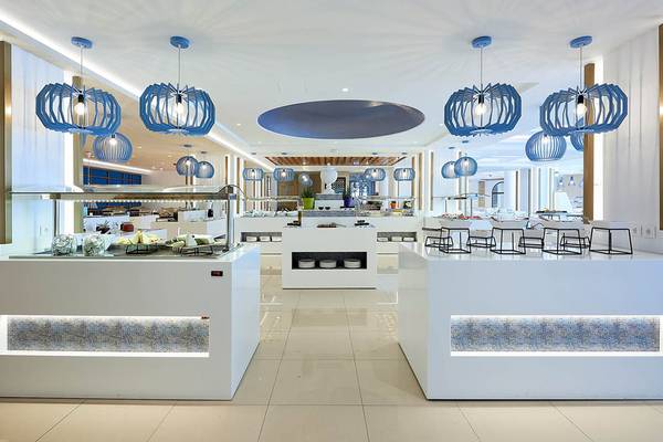 Innenansicht des Buffets im Mythos Palace Resort & Spa mit weißen Tischen, blauen Lampen und verschiedenen Speisen.