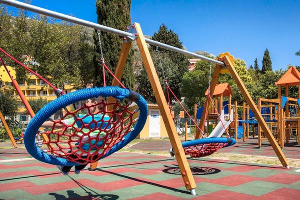 Ein Kind spielt auf einem blauen Netzschaukel am Remisens Hotel Epidaurus Kinderspielplatz.