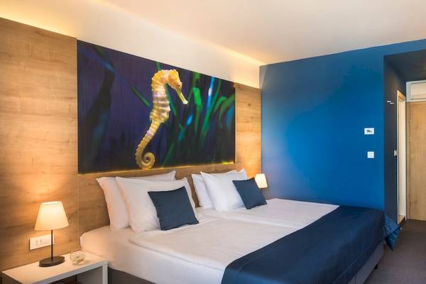 Innenansicht eines Doppelzimmers im Remisens Hotel Epidaurus mit blauen Wänden und einem großen Wandbild von einem Seepferdchen.