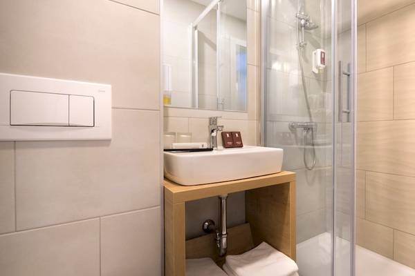 Badezimmer im Remisens Hotel Epidaurus mit weißem Waschbecken und Duschkabine.