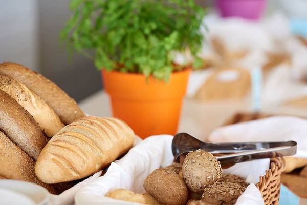 Verschiedene Brotsorten und Getreide in einem Korb mit einem kleinen Topf im Hintergrund.