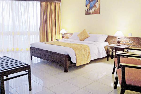 Schlafzimmer im Kenya Bay Beach Hotel mit Doppelbett, Nachttischen und Lampen.
