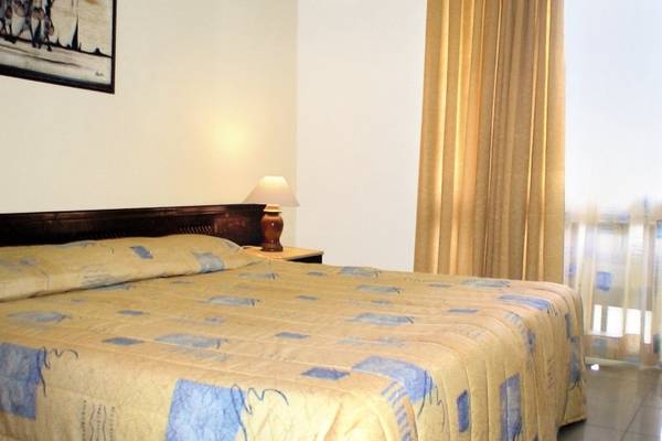 Schlafzimmer im Kenya Bay Beach Hotel mit einem Bett, Nachttisch und Lampe.