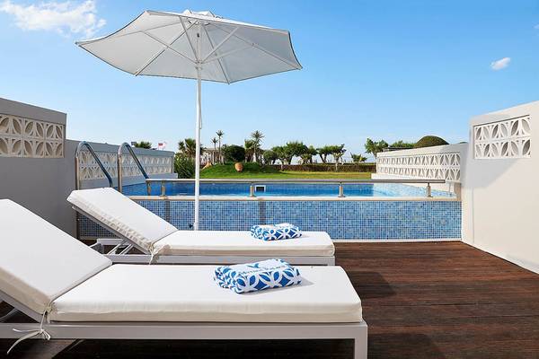 Mythos Palace Resort & Spa Dachterrasse mit zwei Sonnenliegen und einem Pool.