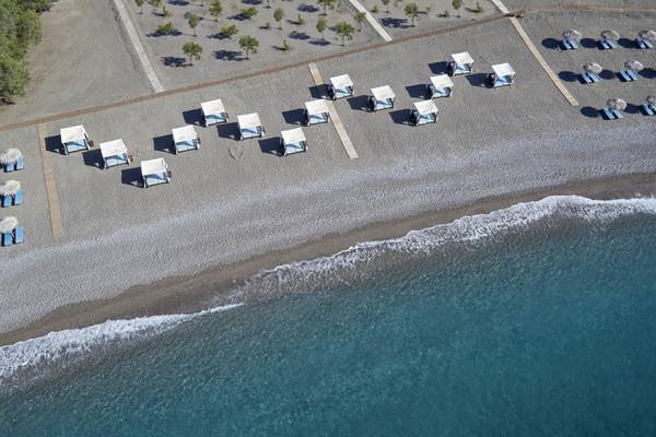 Luftaufnahme des Lindian Village Beach Resorts Strands mit blauen Sonnenschirmen und weißen Liegen