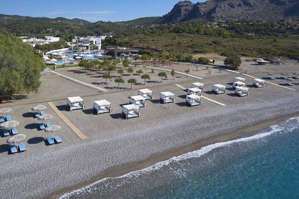 Luftaufnahme des Lindian Village Beach Resort auf Rhodos mit Strand, Liegen und Hotelgebäuden.