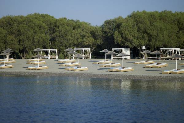 Strand des Lindian Village Beach Resort auf Rhodos mit vielen Liegen und Sonnenschirmen.