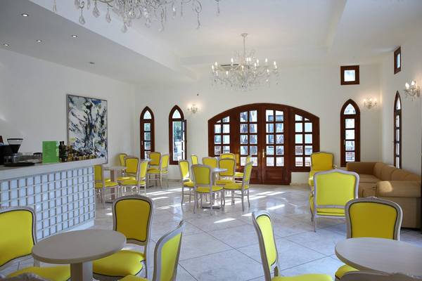 Lobby des Lindian Village Beach Resort auf Rhodos mit gelben Stühlen und Tischen.