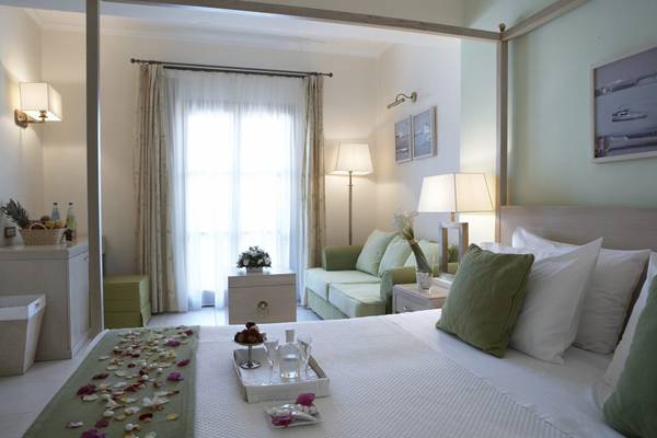 Hotelzimmer im Lindian Village Beach Resort Rhodes mit Bett, Sofa und Fenstern.