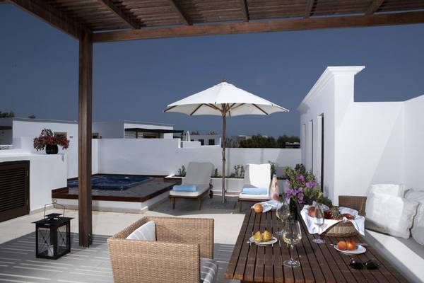 Terrasse des Lindian Village Beach Resort auf Rhodos mit Whirlpool, Sonnenschirm, Tisch mit Obst und Weingläsern