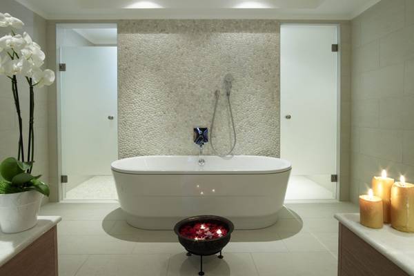 Badezimmer im Lindian Village Beach Resort Rhodes mit Badewanne, Steinwand und Kerzen.