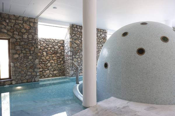 Innenpool des Lindian Village Beach Resort auf Rhodos mit Steinwänden und einem großen, runden Element
