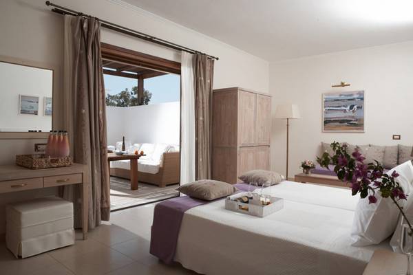 Innenansicht eines Zimmers im Lindian Village Beach Resort in Rhodos, mit offenem Balkon und Blick auf eine Terrasse.