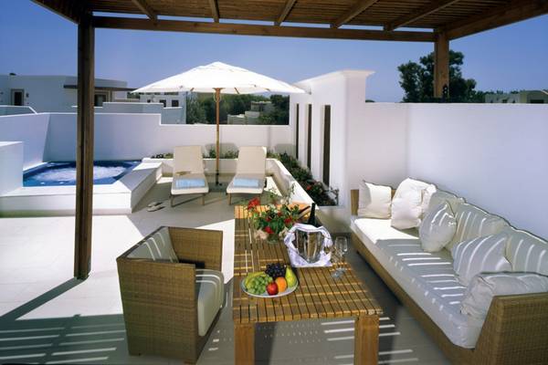 Terrasse des Lindian Village Beach Resort auf Rhodos mit Pool, Sonnenschirm und Möbeln.