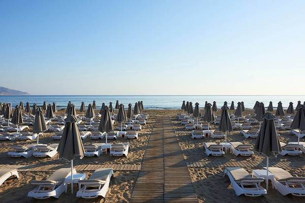 Mythos Palace Resort & Spa Strand mit vielen Sonnenliegen und Sonnenschirmen