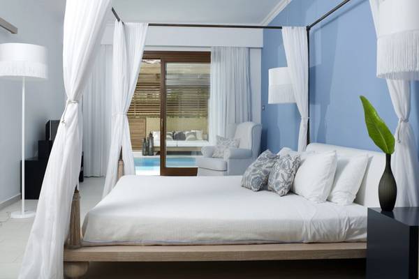Ein Schlafzimmer im Lindian Village Beach Resort in Rhodos mit einem blauen Himmelbett, weißen Vorhängen und Möbeln.