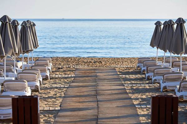 Strand des Mythos Palace Resort & Spa mit weißen Liegestühlen und Sonnenschirmen
