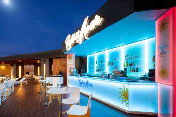 Hotelbar auf der Terrasse bei Nacht mit blauen und roten Beleuchtungselementen.