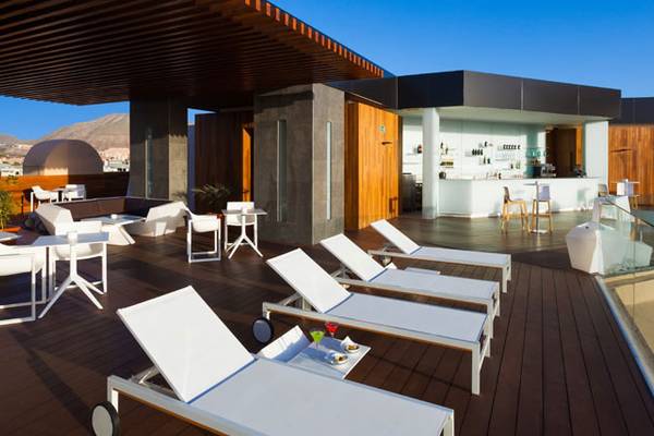 Außenbereich des Tigotan Lovers & Friends Hotels mit Loungestühlen und Tischen auf einer Dachterrasse.