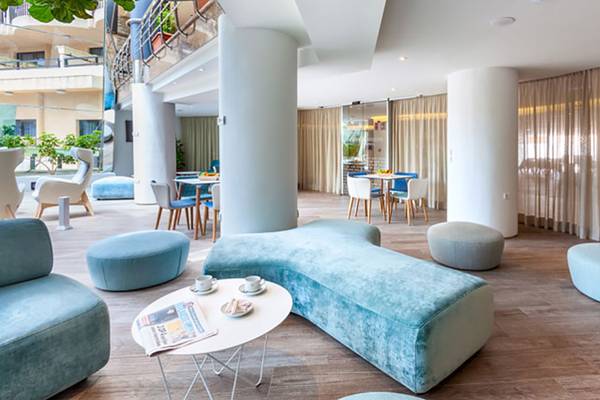 Lounge-Bereich des Tigotan Lovers & Friends Hotels mit blauen Möbeln, einem Tisch und einer Zeitschrift.