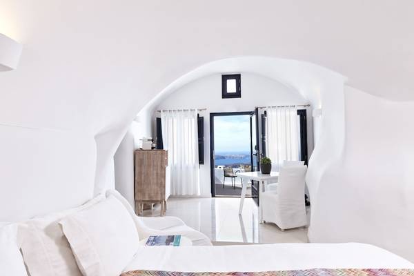 Innenansicht eines Zimmers im Katikies Chromata Santorini Hotel mit Blick auf den Ozean.