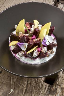Beetroot-Platte mit verschiedenen Toppings auf einem schwarzen Teller.