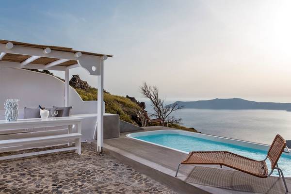 Terrasse mit Sitzecke und Pool im Katikies Chromata Hotel auf Santorini mit Meerblick.
