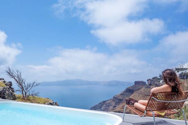 Frau sitzt auf einer Terrasse des Katikies Chromata Santorini und genießt den Blick auf das Meer.