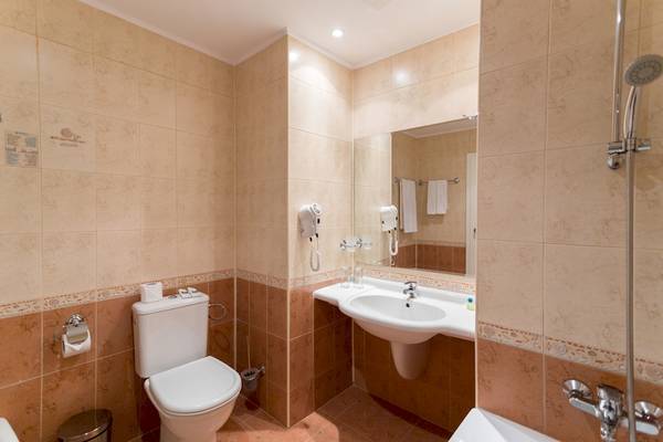 Badezimmer im DIT Evrika Beach Club mit Toilette, Waschbecken, Spiegel und Dusche.