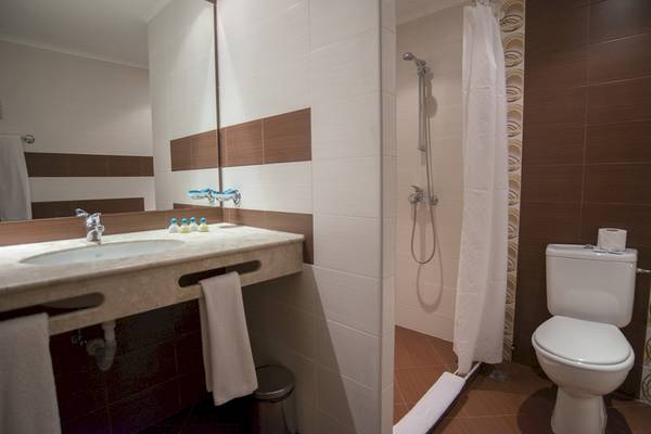 Badezimmer im DIT Evrika Beach Club mit Dusche, Toilette und Waschbecken.