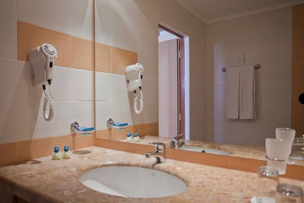 Badezimmer im DIT Evrika Beach Club mit Spiegel, Handtuchtrockner und Waschbecken.