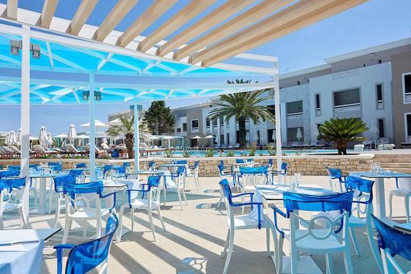 Restaurant im Mythos Palace Resort & Spa mit blauen Stühlen und Tischen unter einem Pavillon.