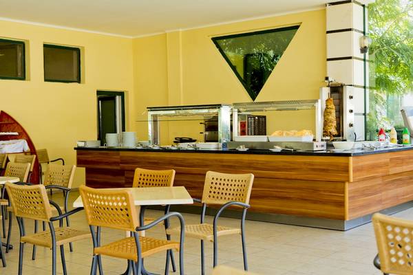 Innenansicht des Restaurants des DIT Evrika Beach Club Hotels mit gelben Wänden und hölzerner Theke.