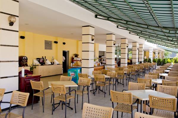 Innenbereich des DIT Evrika Beach Club Hotels mit vielen Tischen und Stühlen.