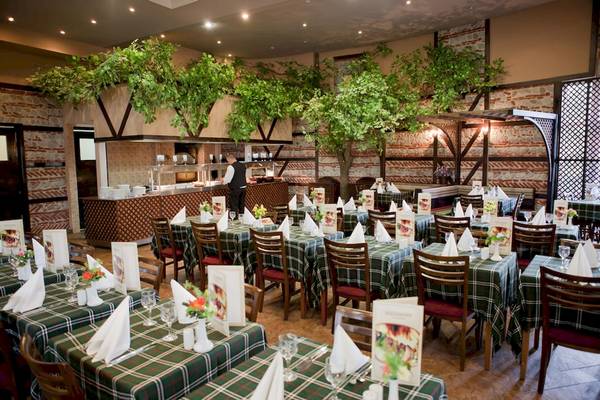 Innenansicht des DIT Evrika Beach Club Restaurants mit gedeckten Tischen und Bäumen.