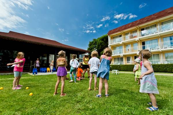 Mehrere Kinder spielen auf dem Rasen vor dem DIT Evrika Beach Club Hotel.