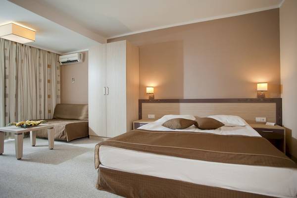 Foto eines Hotelzimmers im DIT Evrika Beach Club Hotel mit Bett, Nachttisch, Lampe und Schlafsofa.