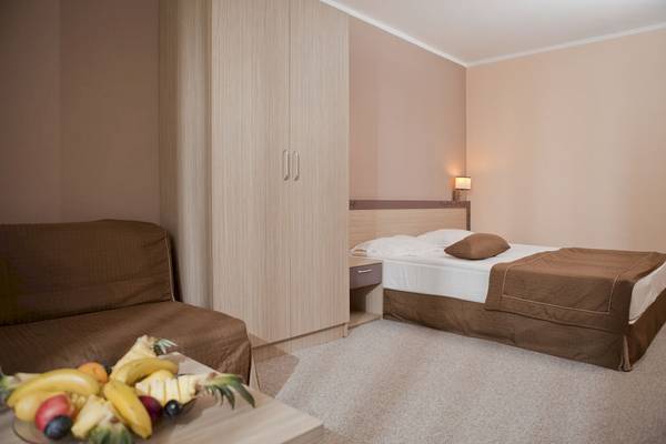 Foto eines Hotelzimmers im DIT Evrika Beach Club mit einem Bett, einer Kommode und einem Tisch mit Obst.