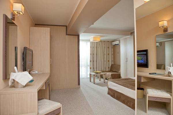 Hotelzimmer im DIT Evrika Beach Club mit Schreibtisch, Fernseher, Bett und Sitzbereich.