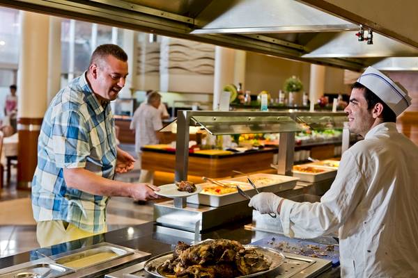 Ein Mitarbeiter serviert Essen in einem Restaurant im DIT Evrika Beach Club Hotel.