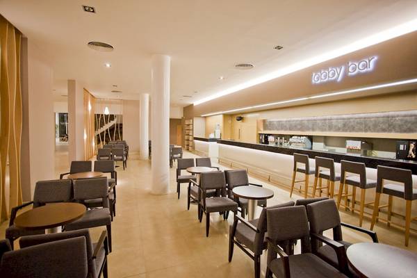 Innenansicht der Lobby Bar des DIT Evrika Beach Club mit Sitzgelegenheiten und einer Theke.