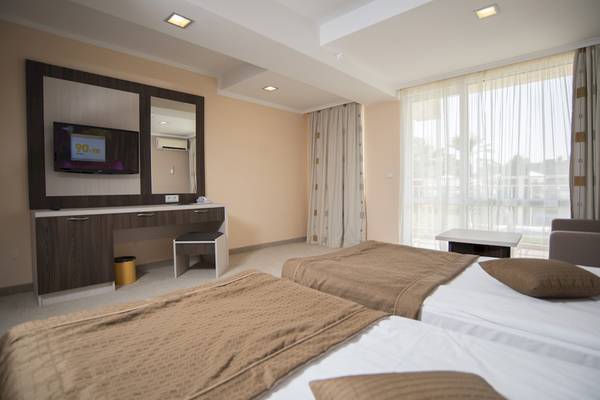 Doppelzimmer im DIT Evrika Beach Club Hotel mit zwei Betten, Fernseher, Schreibtisch und Spiegel.